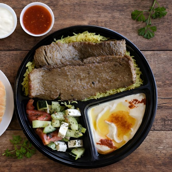 Gyro meat and yellow rice with a side salad and hummus in a black to-go container.